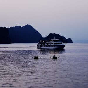 A rowboat on a calm ocean, mountain in the background.